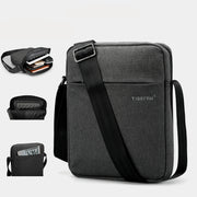 Gray shoulder bag with a black strap, on a white background.