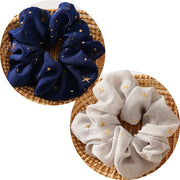 Two scrunchies, one blue and one white, with star patterns on a woven surface.