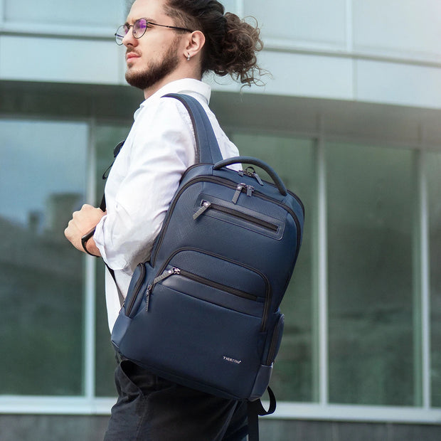 Man wearing a blue backpack outdoors with a modern building in the background