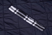 Close-up of a navy quilted jacket with a white and black striped pattern on a matching background