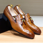 Brown leather shoes with tassels on a wooden surface