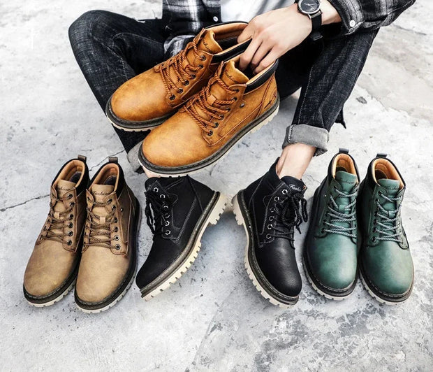 Person holding brown leather boots with four other pairs of boots displayed on a concrete floor