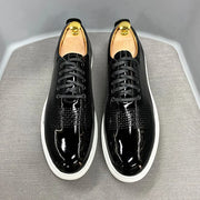 Black patent leather shoes with white soles on a gray surface