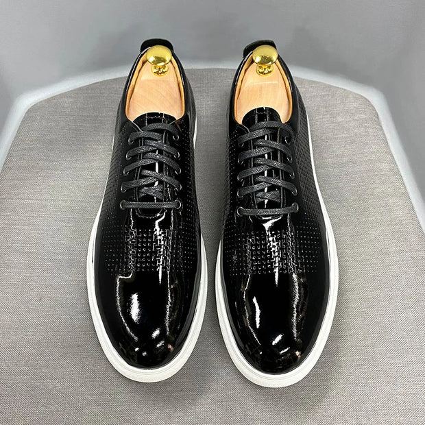 Black patent leather shoes with white soles on a gray surface