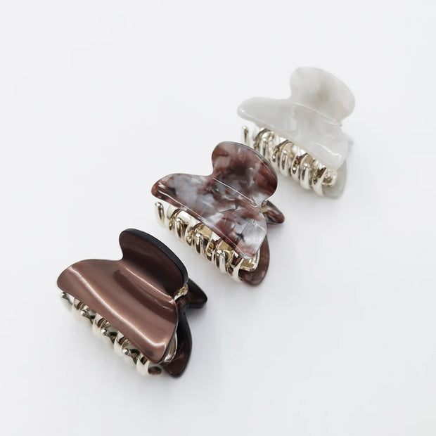 Set of four hair clips with marble and metallic designs on a white background