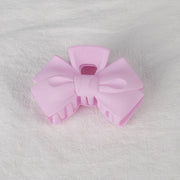 Pink hair bow clip on a textured gray background