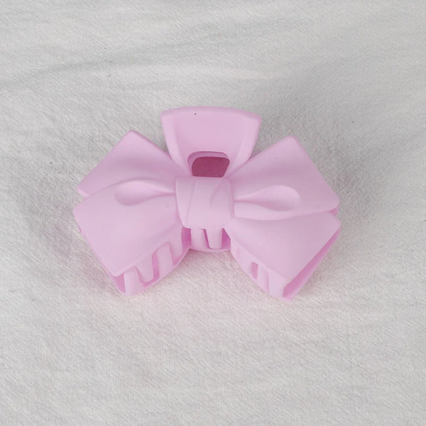 Pink hair bow clip on a textured gray background