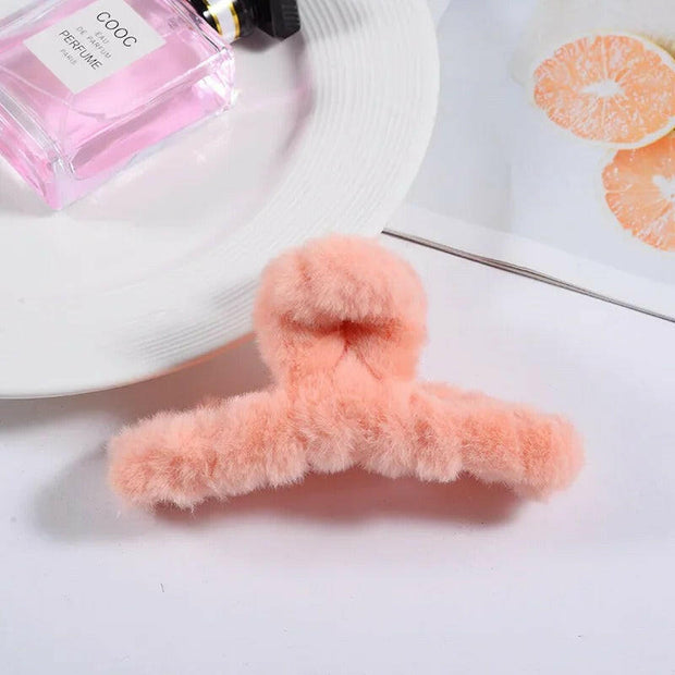 Pink fluffy hanger on a white surface with a pink perfume bottle in the background.