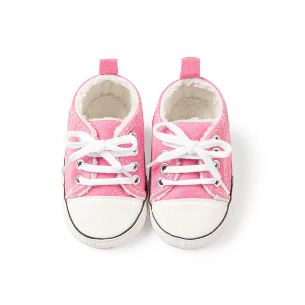 Pair of pink baby sneakers with white laces on a white background