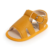 Yellow baby sandal with a buckle on a white background