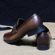 Pair of brown leather loafers on a textured surface with a dark background