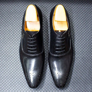 Black dress shoes with gold soles on a textured gray background