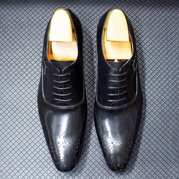 Black dress shoes with gold soles on a textured gray background