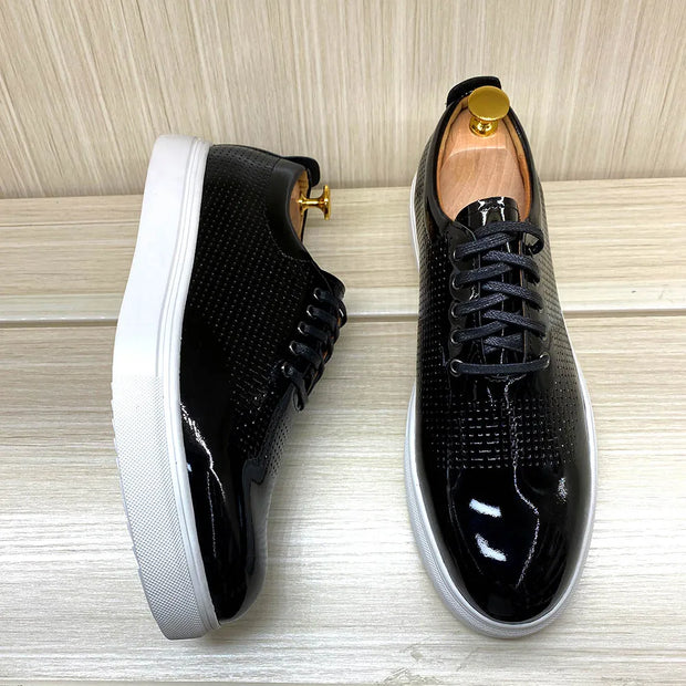 Black patent leather shoes with white soles on a wooden surface