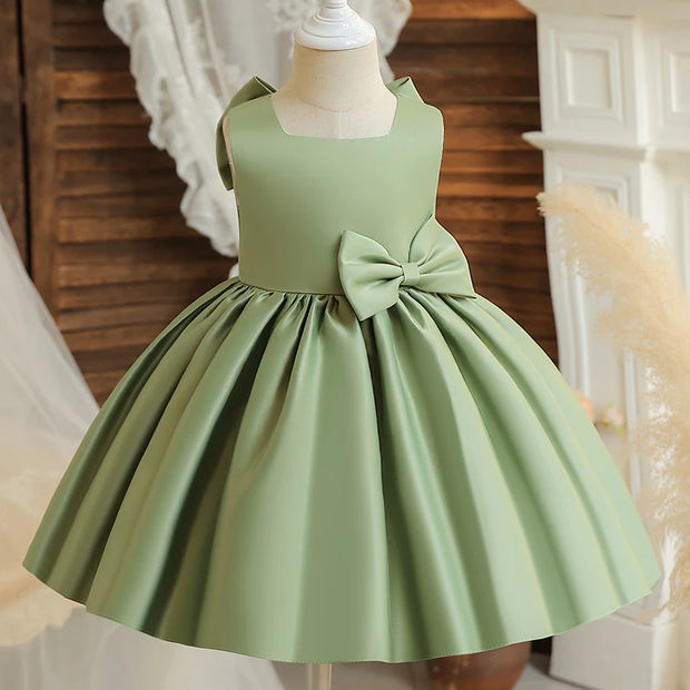 Green dress with a large bow on a mannequin against a neutral background