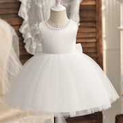 White flower girl dress on a mannequin with a blurred background