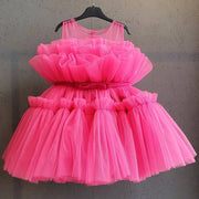 Pink tulle dress on a hanger against a gray background