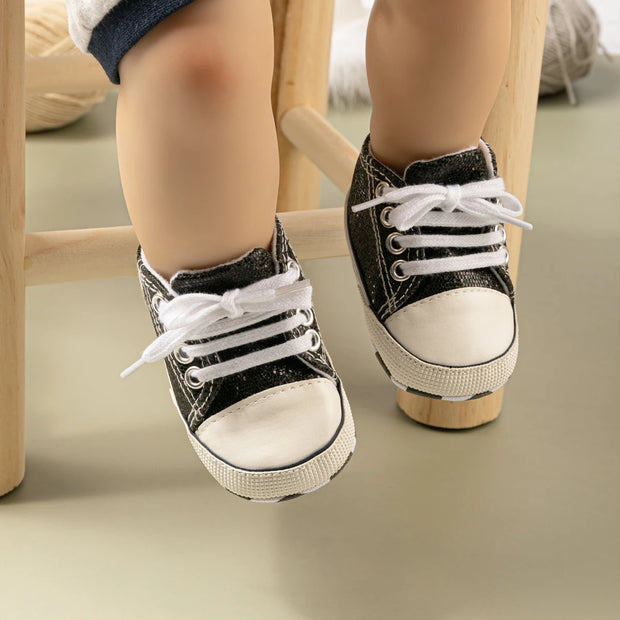 Black and white sneakers worn by a child on a wooden stool.