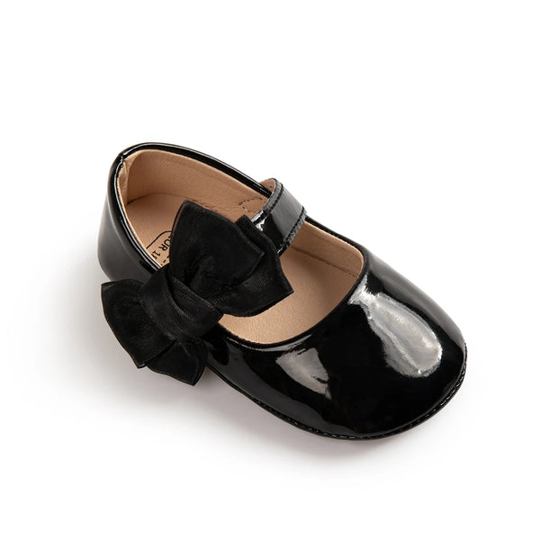 Black patent leather shoe with a bow on a white background