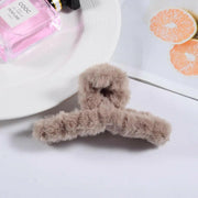 Fluffy brown hanger on a white surface with a pink perfume bottle and orange slices in the background.