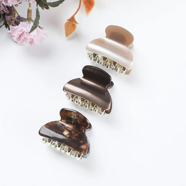 Three tortoiseshell hair clips on a white background with floral decorations.