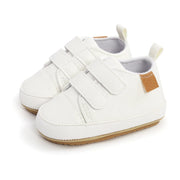 White baby shoes with velcro straps on a white background