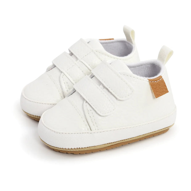 White baby shoes with velcro straps on a white background
