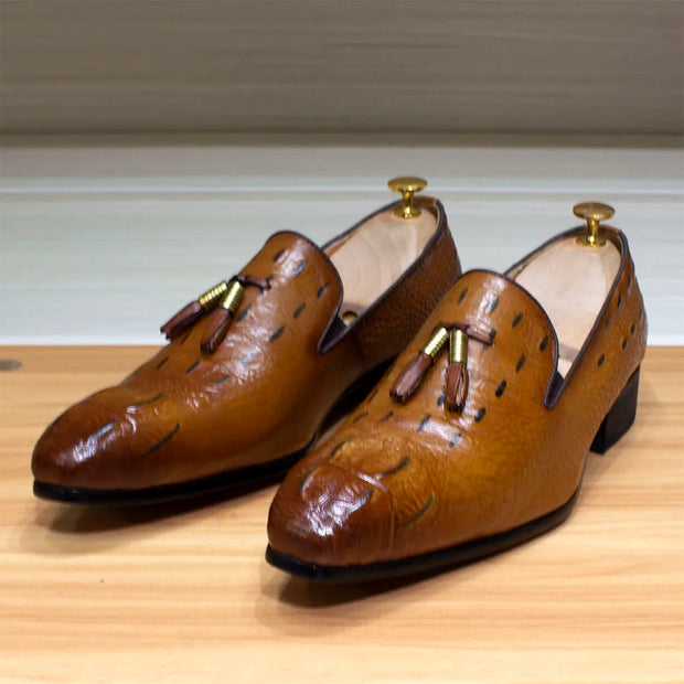 Pair of brown leather loafers with tassels on a wooden surface.