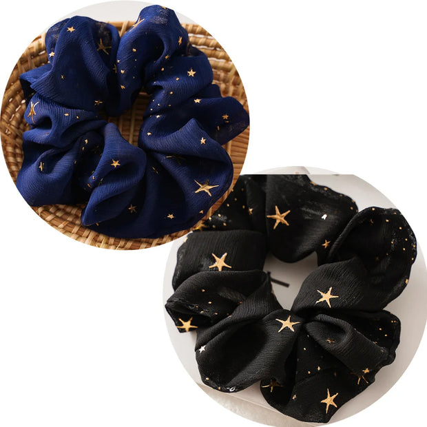 Two scrunchies, one blue and one black, with star patterns on a white background.