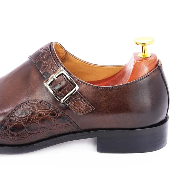 Brown leather dress shoe with a buckle on a white background