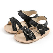 Pair of black and beige baby sandals with buckles on a white background