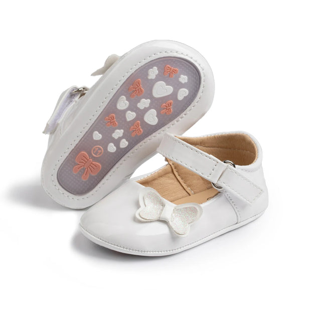 White baby shoes with a bow and heart pattern on the sole against a white background