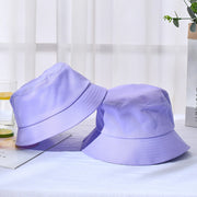 Two purple bucket hats on a light surface with a blurred background