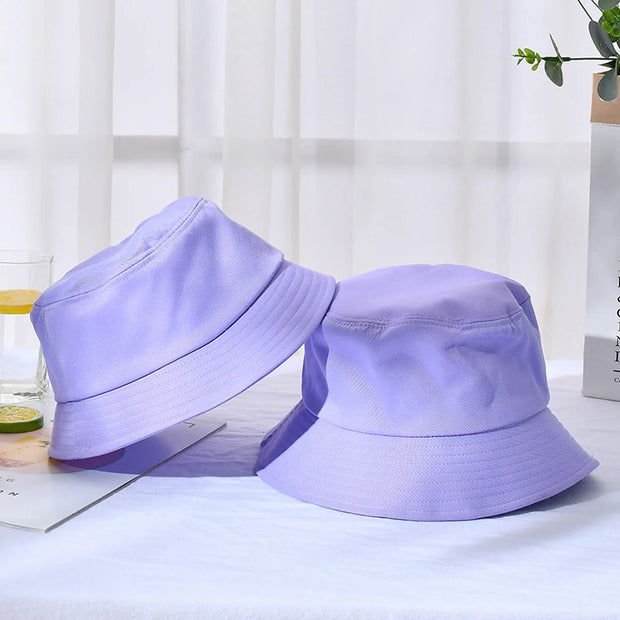 Two purple bucket hats on a light surface with a blurred background