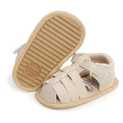 Beige baby sandal with sole showing brand logo on a white background