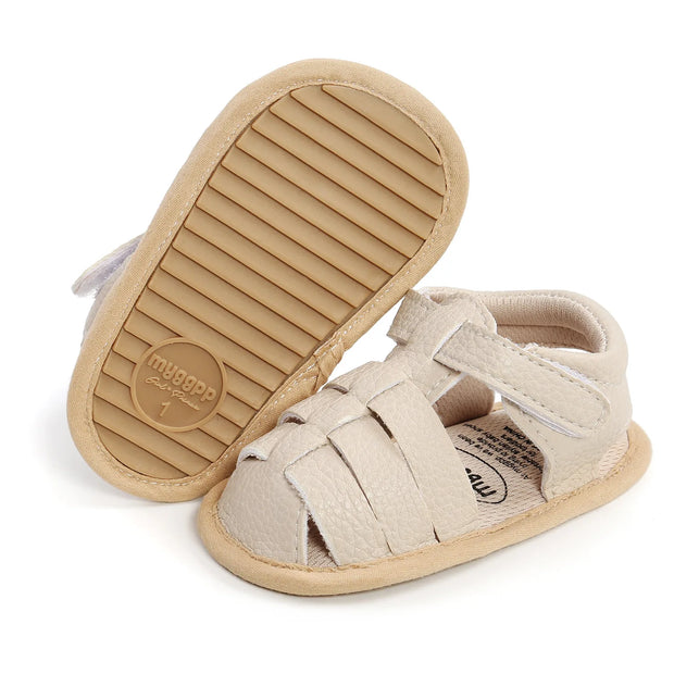 Beige baby sandal with sole showing brand logo on a white background