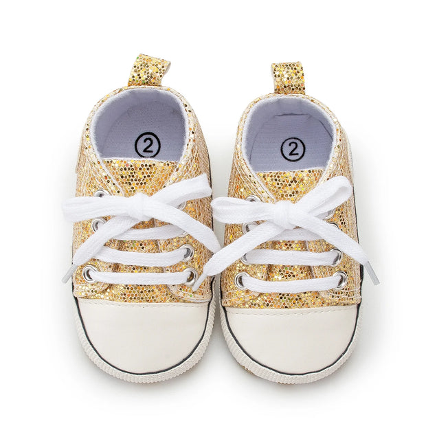 Gold glitter sneakers with white laces on a white background