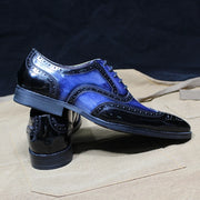 Shiny blue dress shoes on a textured surface with a dark background