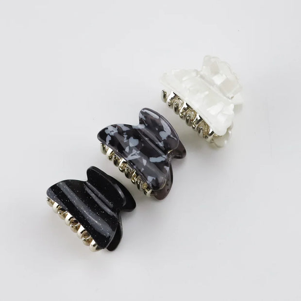 Three hair clips with marble and gold designs on a white background