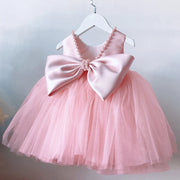 Pink dress with a large bow on a hanger against a light background