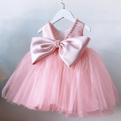 Pink dress with a large bow on a hanger against a light background