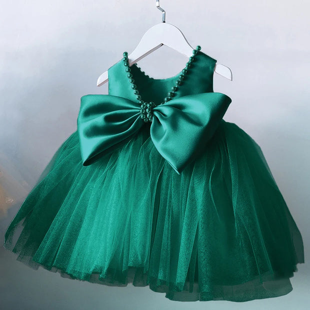 Green dress with a large bow on a hanger against a light gray background