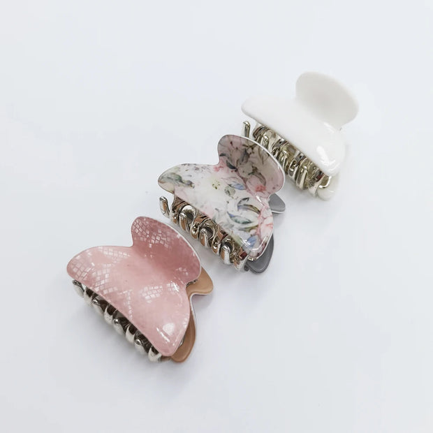 Two decorative hair clips with floral and pink designs on a white background