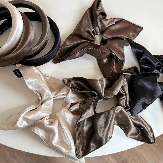 Set of satin scrunchies in various colors on a white surface.