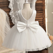 White dress with a large bow on a mannequin against a neutral background