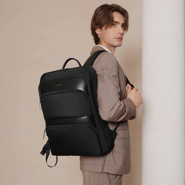 Man in a suit with a black backpack against a beige background