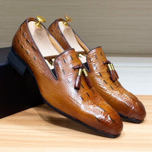 Brown leather loafers with tassels on a wooden surface