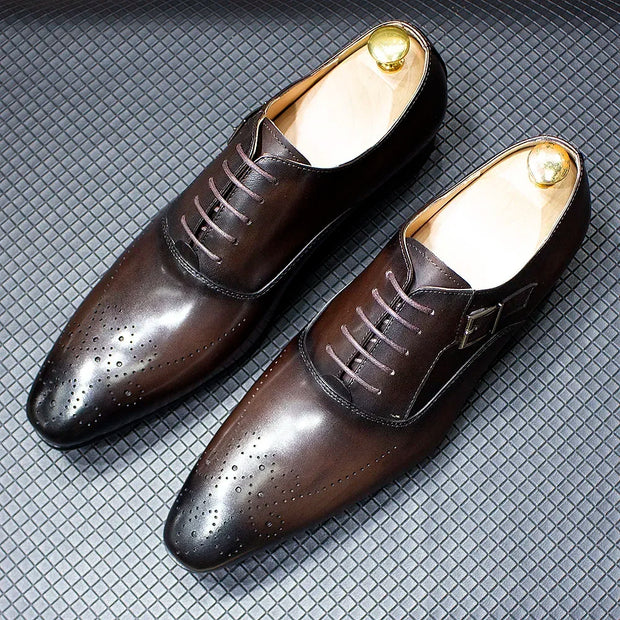 Pair of brown dress shoes with gold accents on a textured gray surface