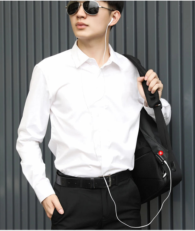 Man wearing a white shirt and black pants, holding a black bag with a red logo against a gray background.