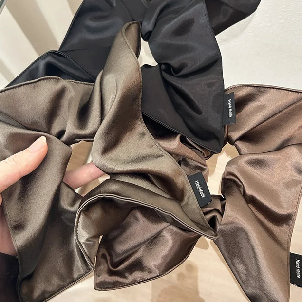 Brown satin fabric with a hand holding it, on a neutral background